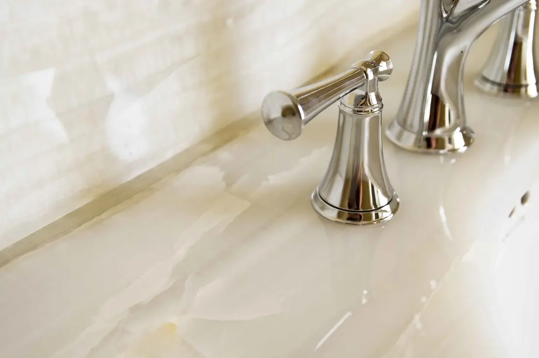 Shiny chrome bathroom faucets on marble sink